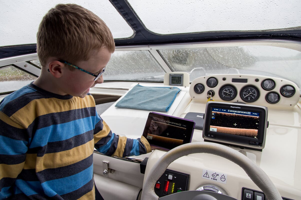 Young boy with glasses looking at a boat sat nav