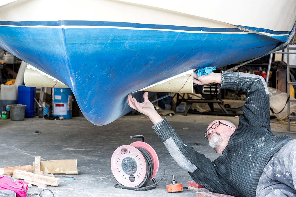 Man fixing the bottom of a boat out of water